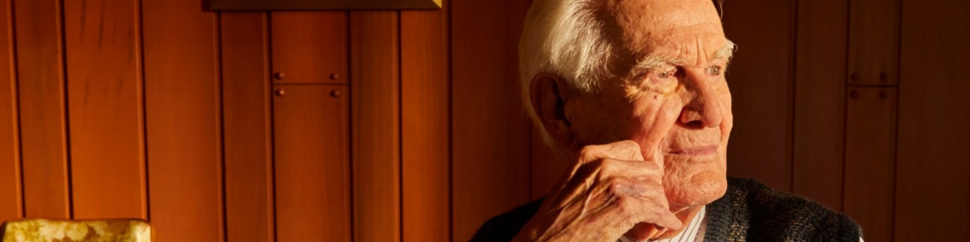 Meals on Wheels clients leans against hand on face at the dinner table, staring into the empty space.