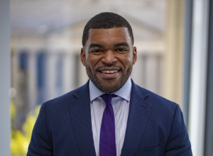 Justin Clayton professional headshot smiling in front of a capitol building.